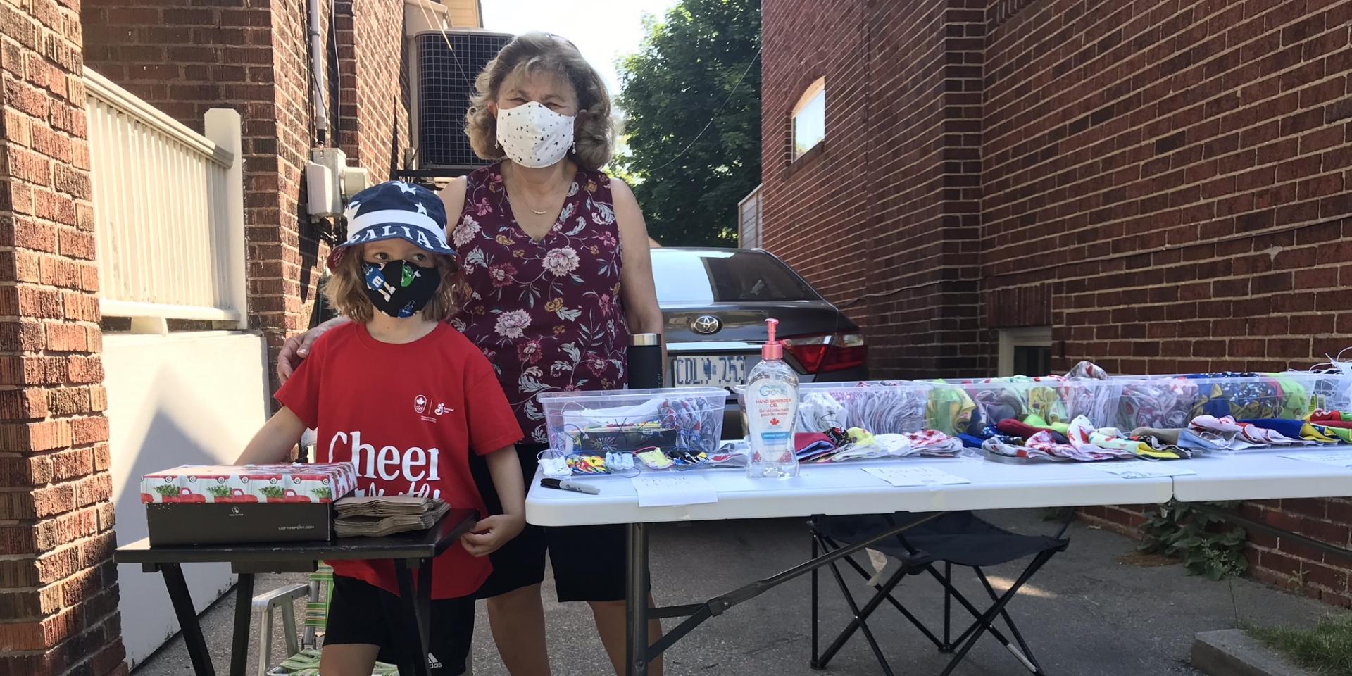 woman and boy standing next to table of masks 