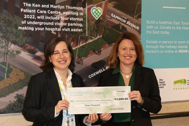 two woman holding a large cheque