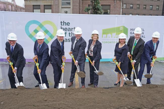 executives pose with shovels in front of HOTE banner