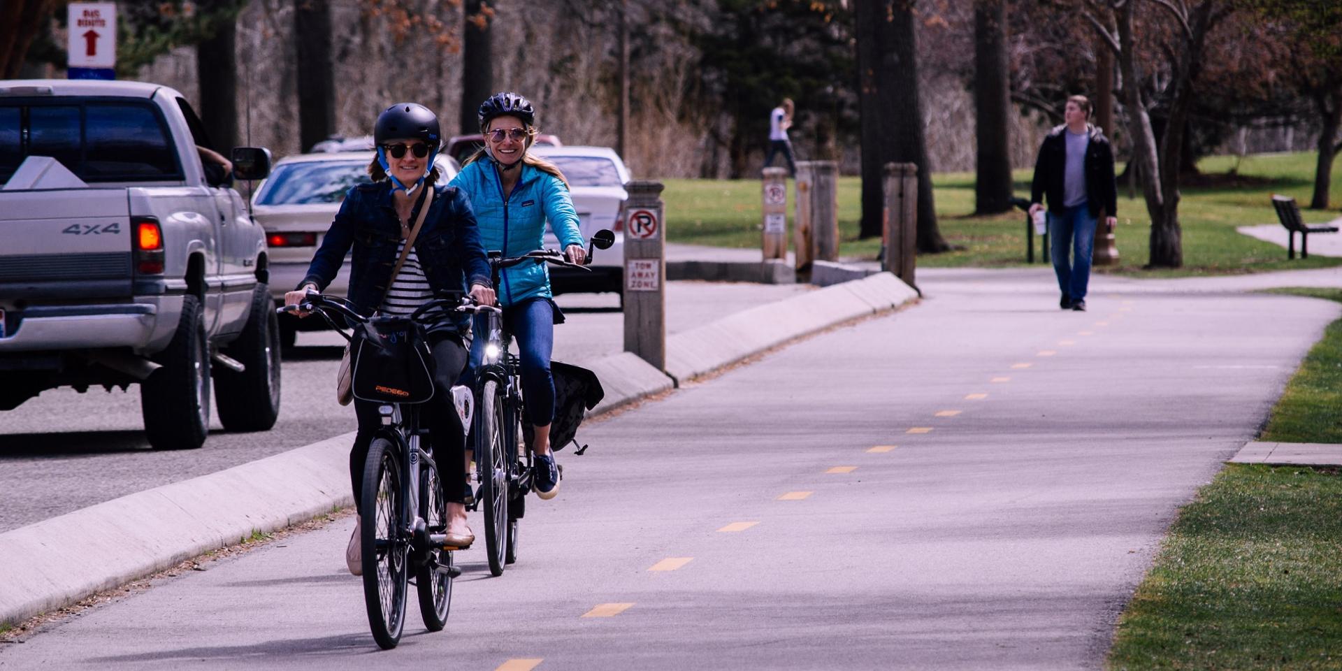 Two women riding bicycles on a bike path 