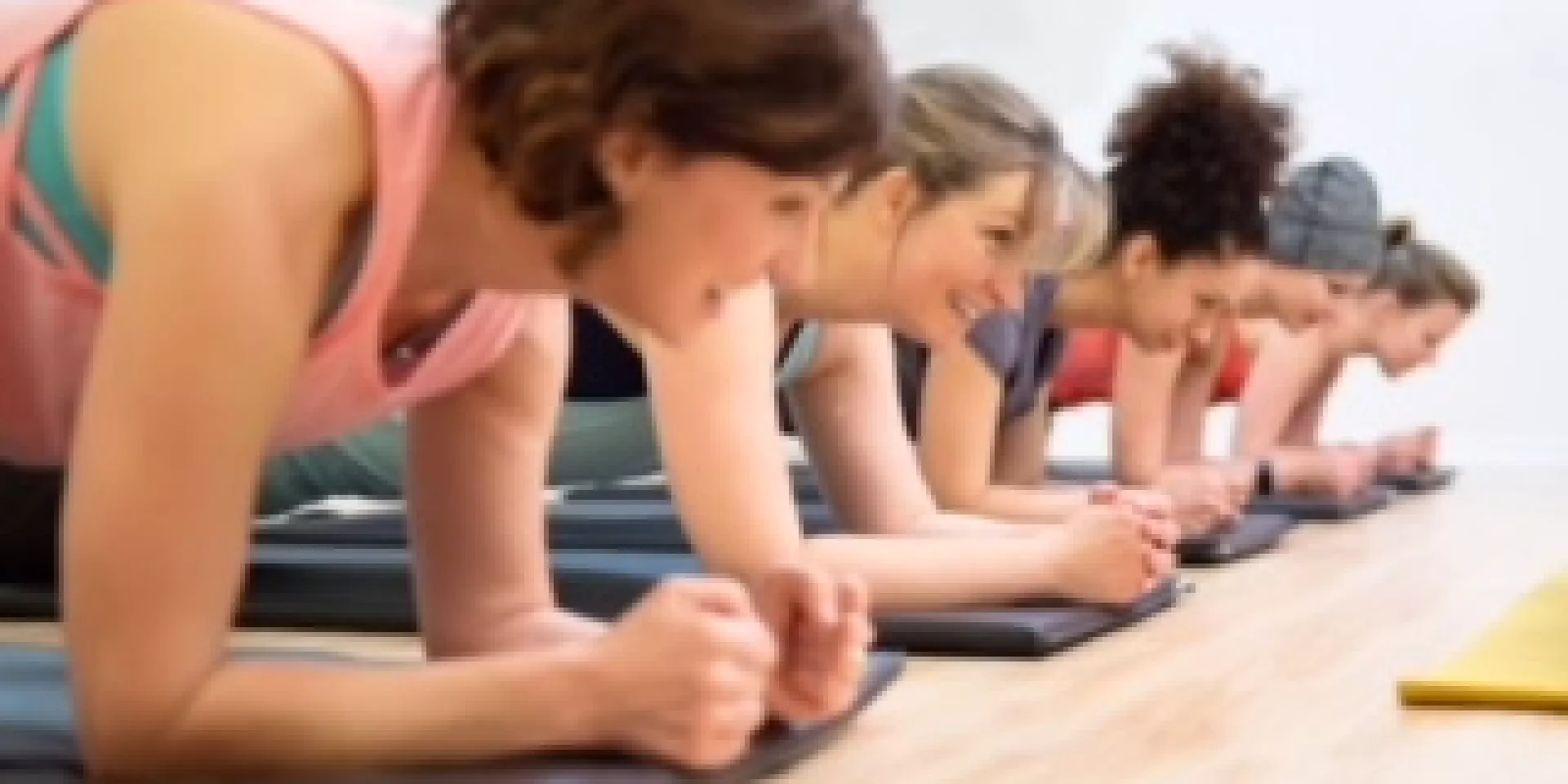 several women in fitness class lying down on forearms 