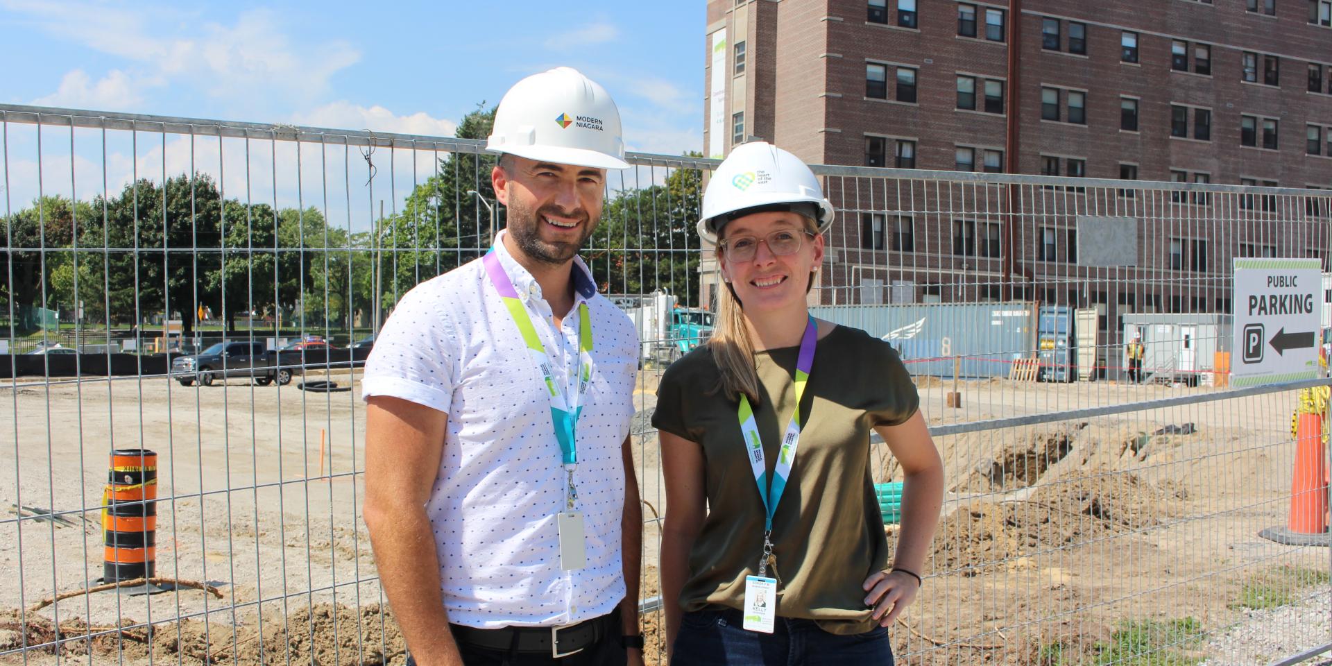 man and woman standing in front of construction site wearing hardhats