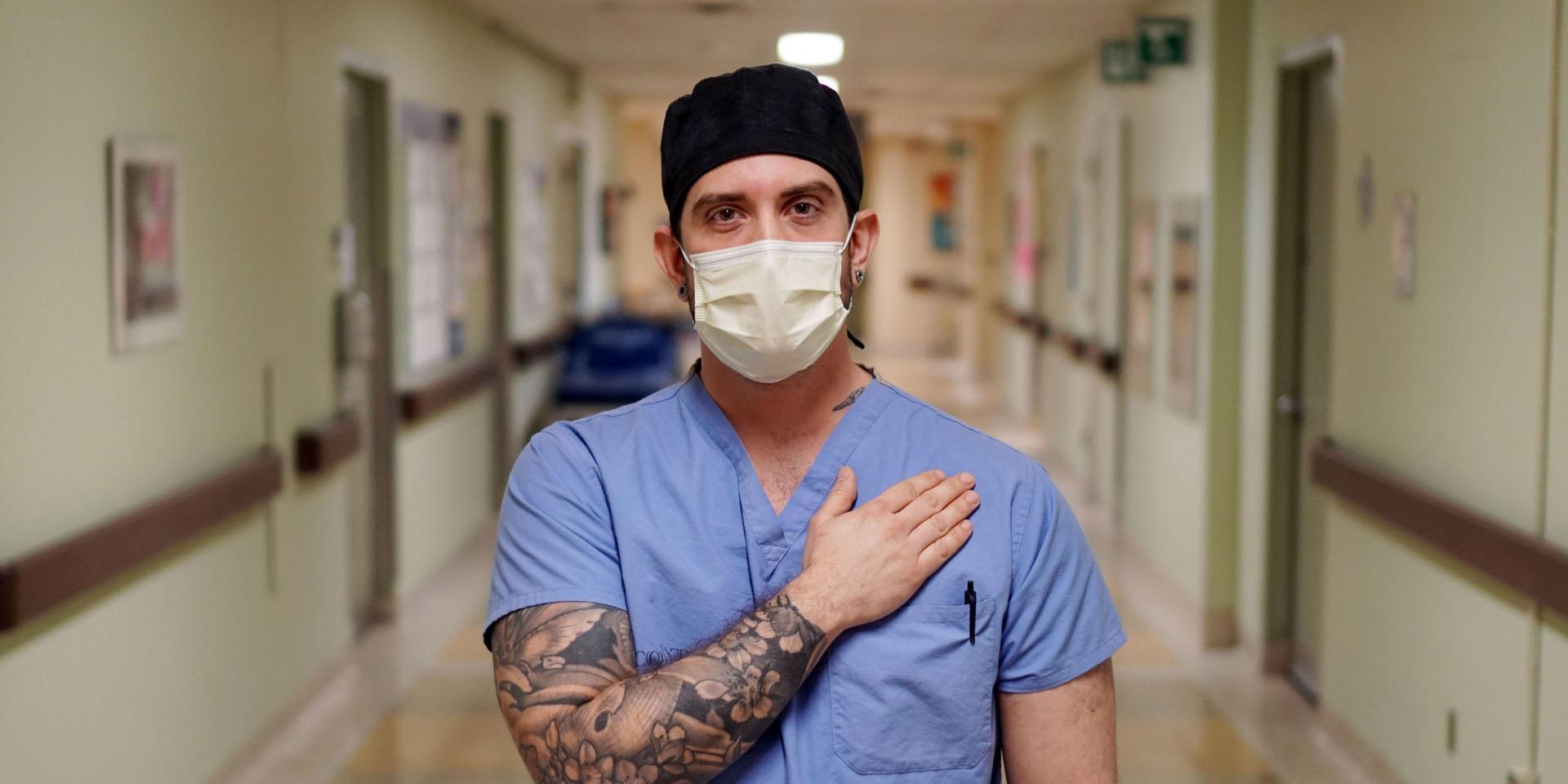 man standing in hospital corridor with hand over heart