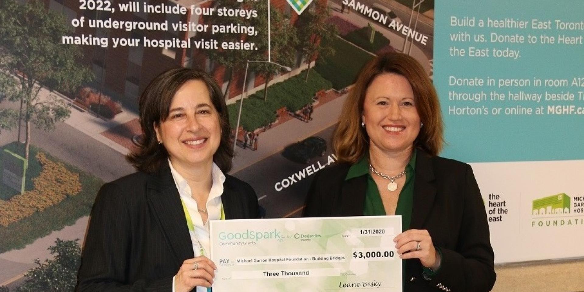 two woman holding a large cheque