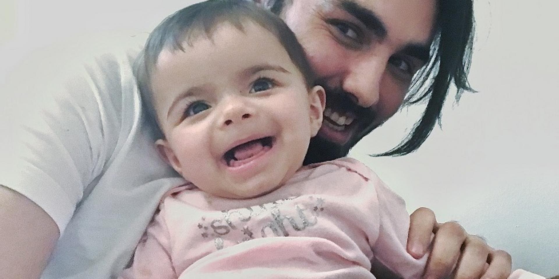 A man holding a baby, both facing the camera