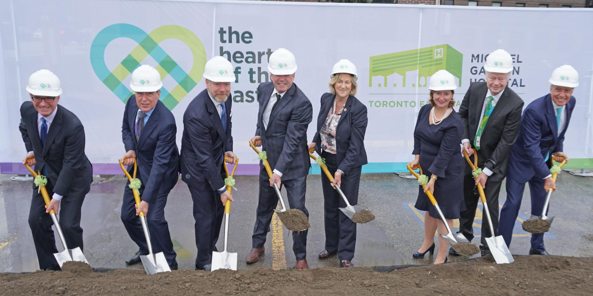 executives pose with shovels in front of HOTE banner