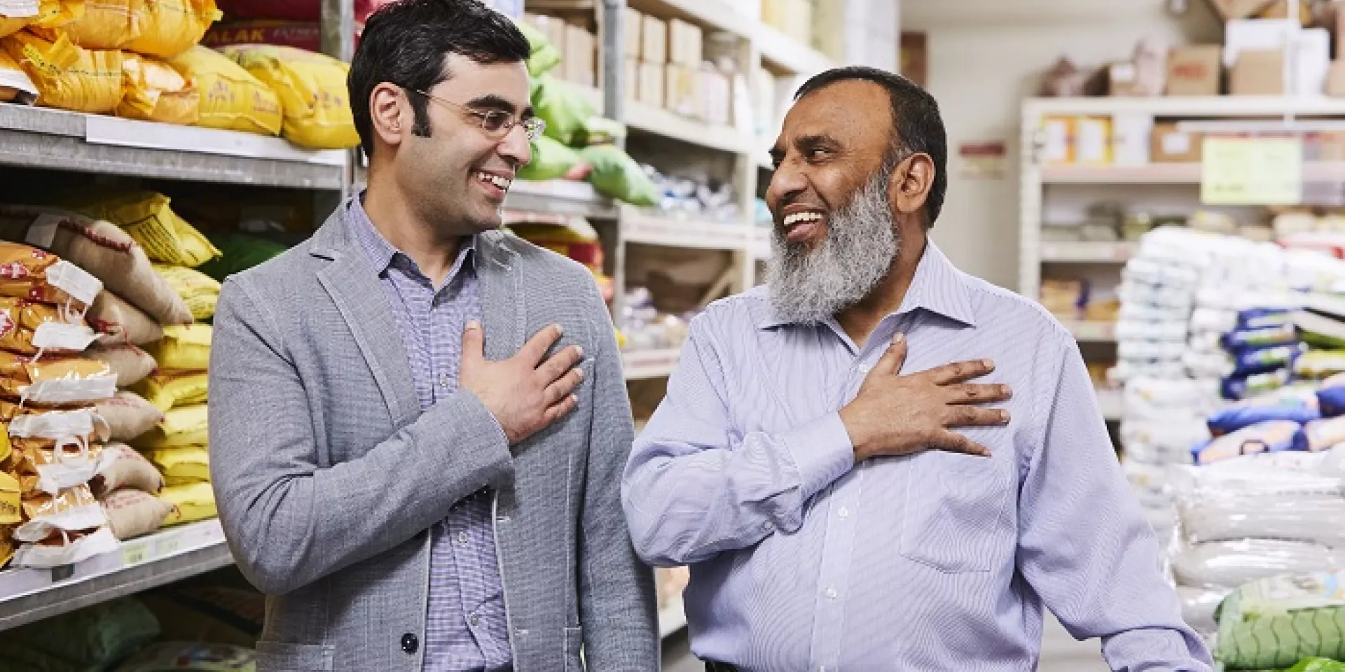 two men standing side by side slightly turned to face each other each with right hand over heart