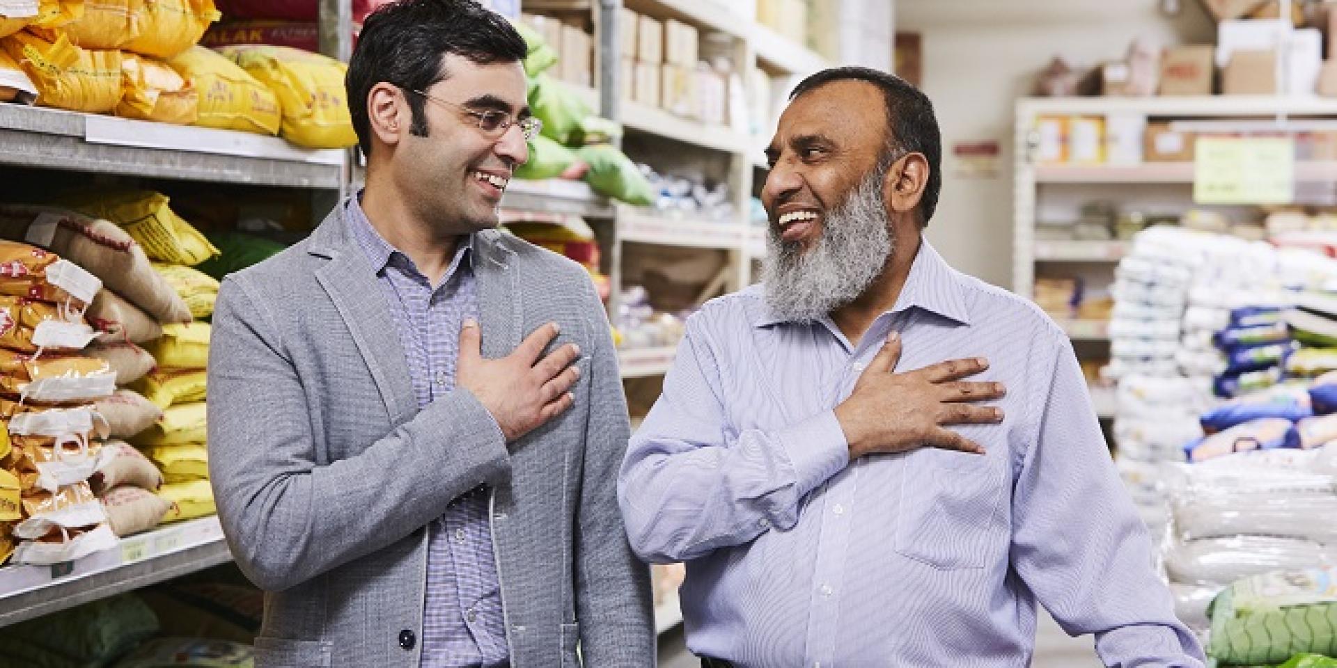 two men standing side by side slightly turned to face each other each with right hand over heart