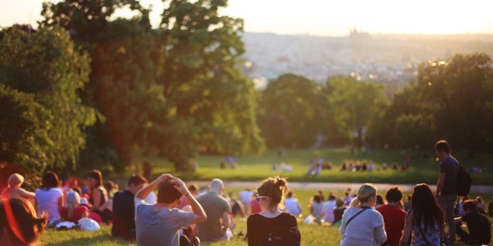 community event view from behind of people sitting on a grassy hill