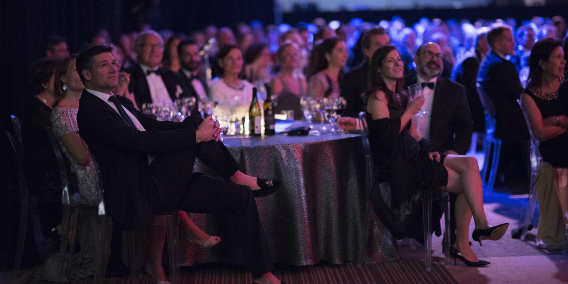 people sitting at tables for gala event dark lit room