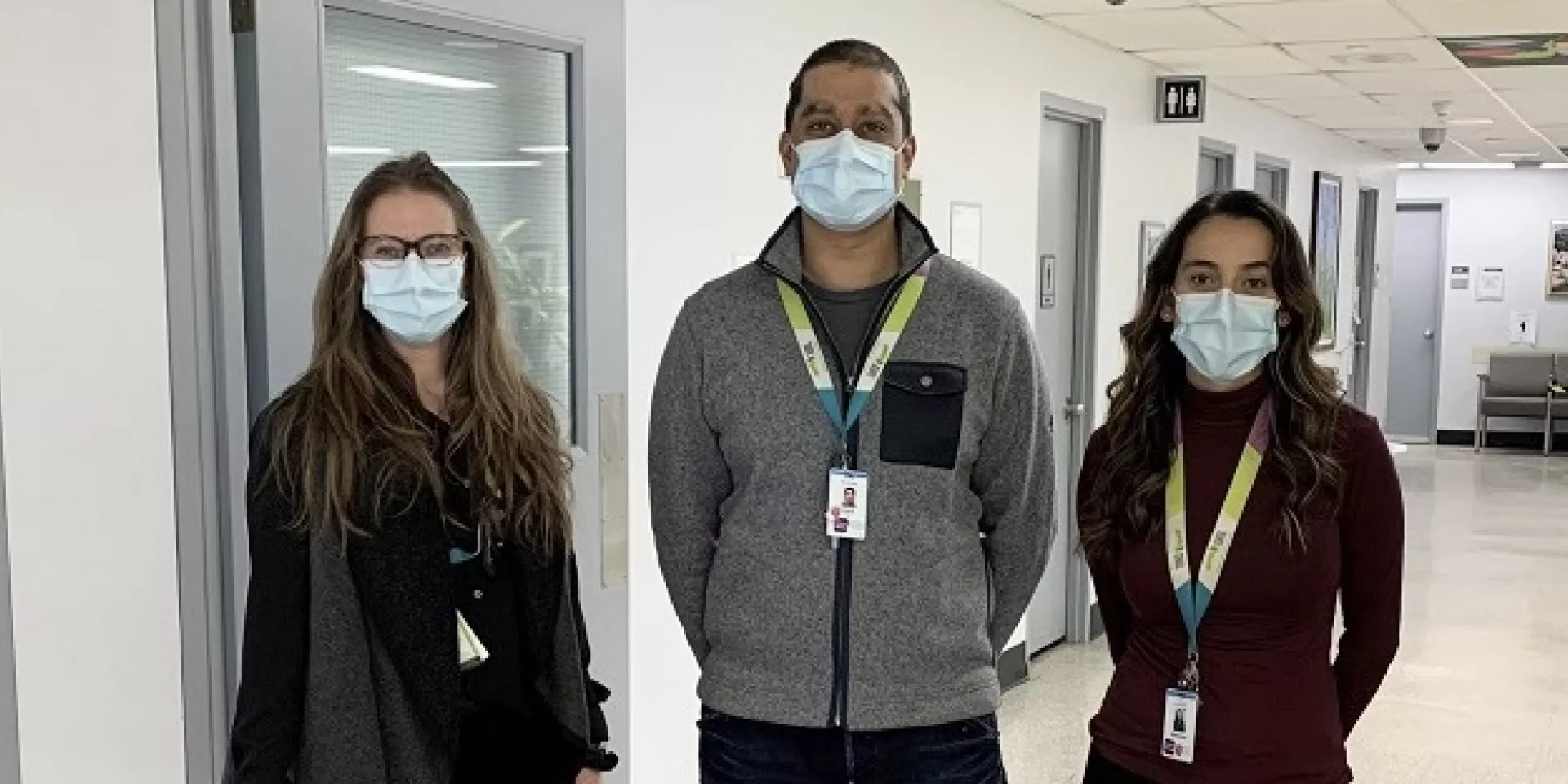 three people standing in corridor facing the camera 