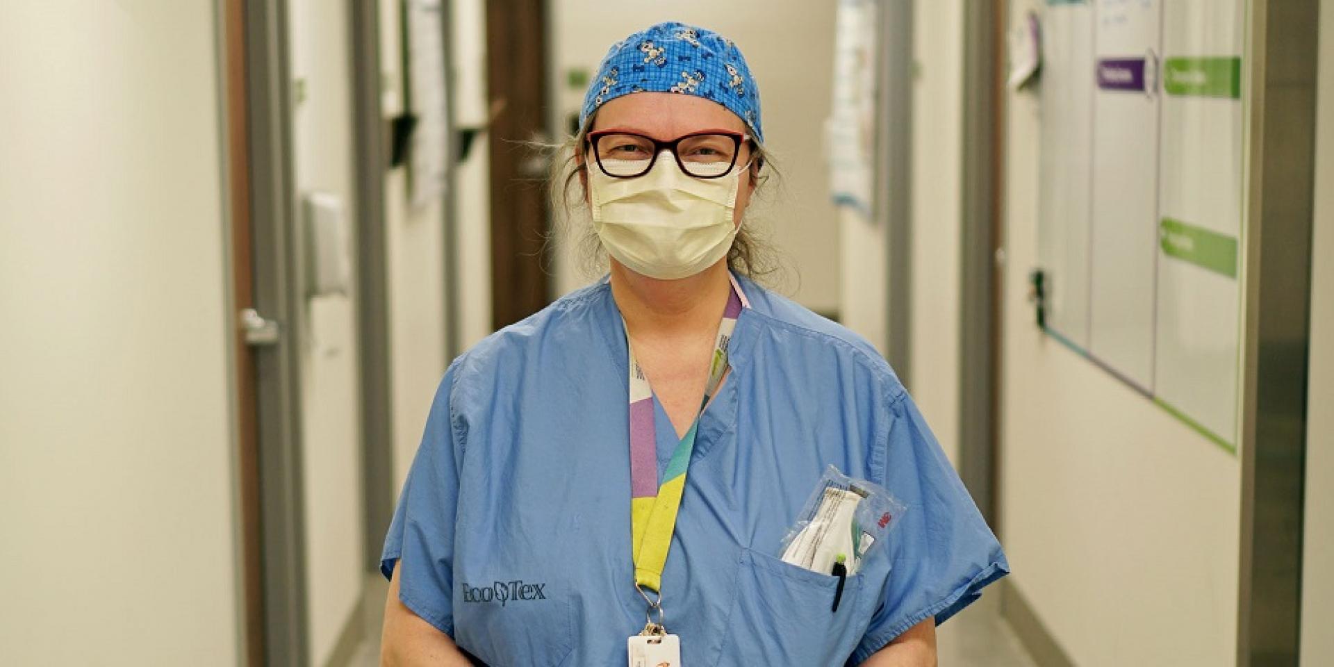 healthcare worker wearing mask standing in hospital corridor