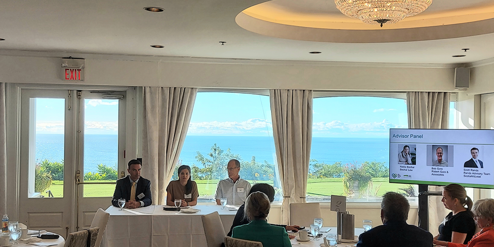 Seven advisors viewing a presentation over breakfast in a bright and sunny room.