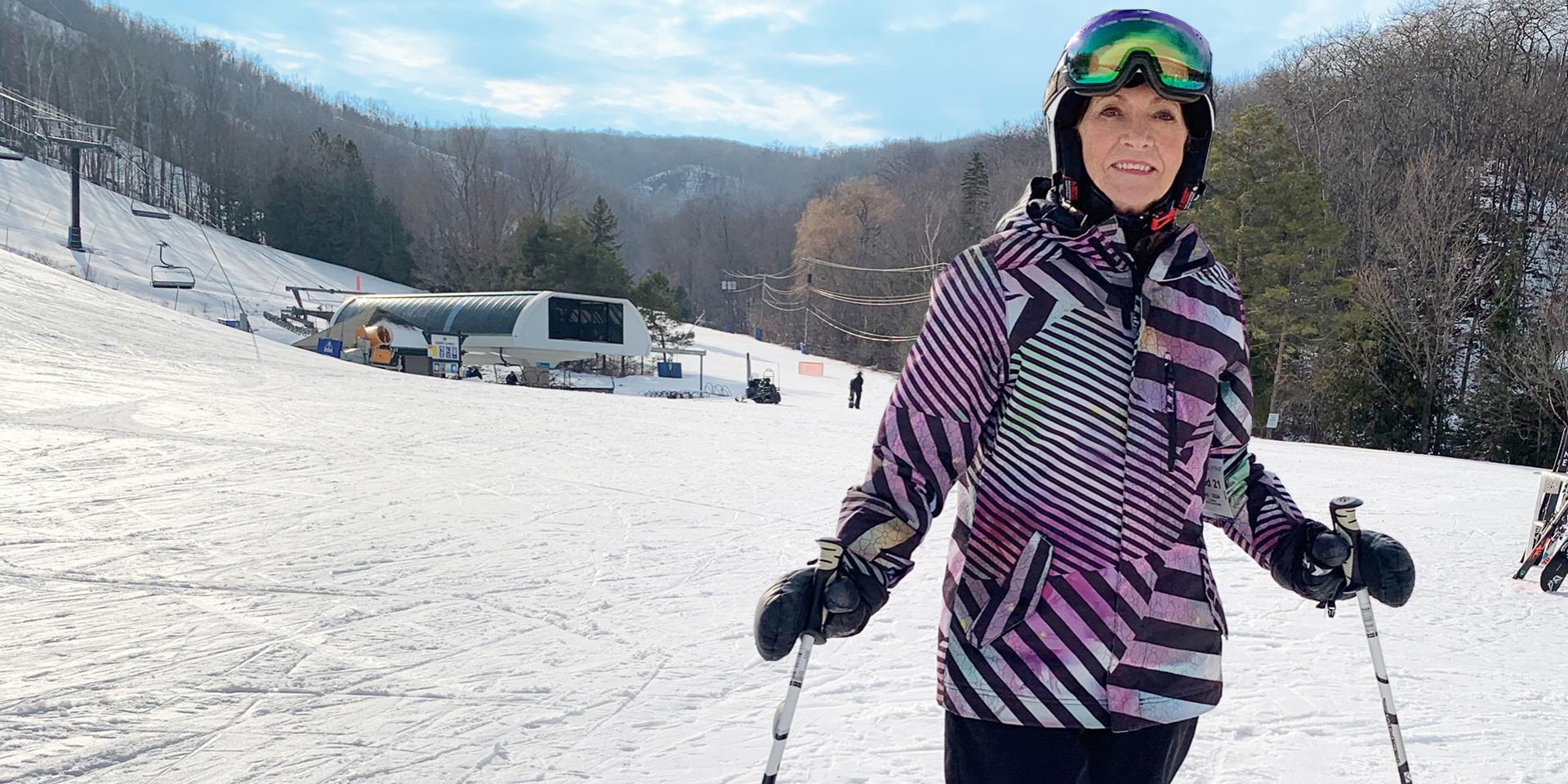 Margrie, an older white woman, on a ski hill with poles and googles.