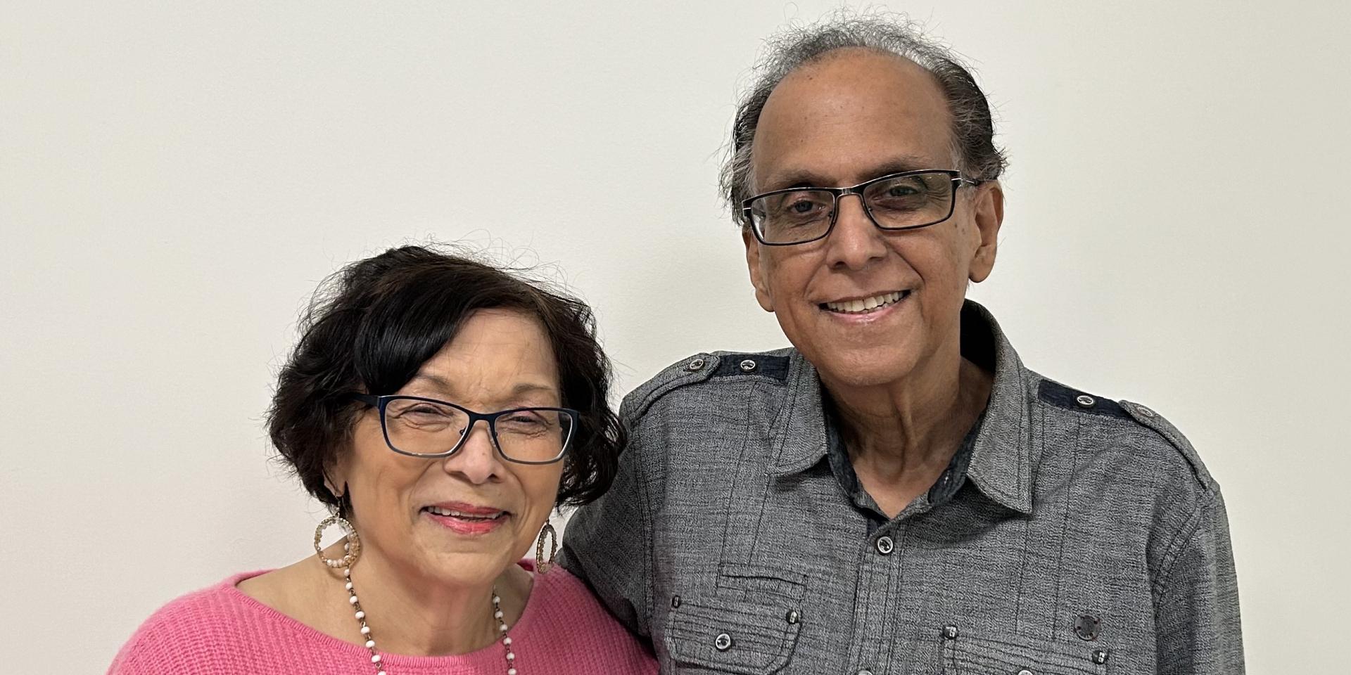 An older couple posed with his arm wrapped around her
