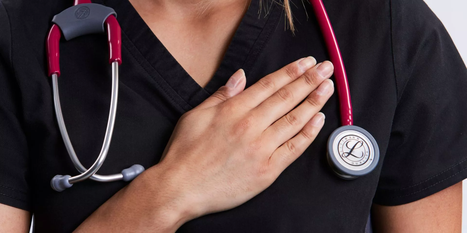 A young physician with their hand over their heart, framed by their stethoscope