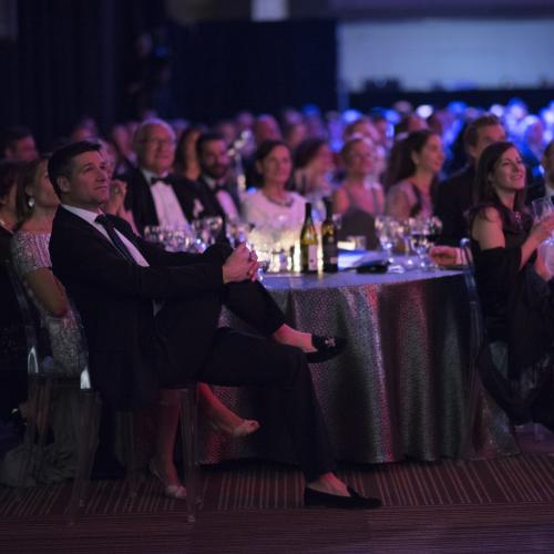 people sitting at tables for gala event dark lit room
