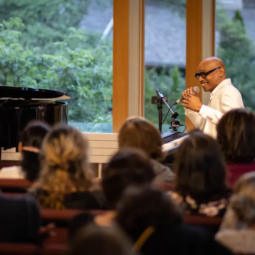 Eddie Bullen sitting at his piano speaking to a crowd