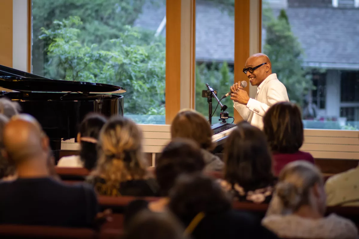Eddie Bullen sitting at his piano speaking to a crowd