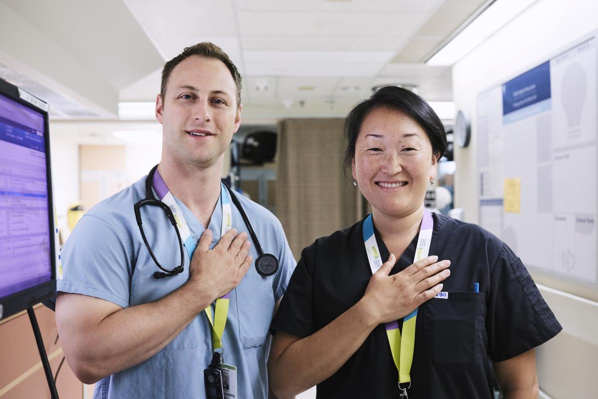 Two hospital staff members with their hands on their hearts