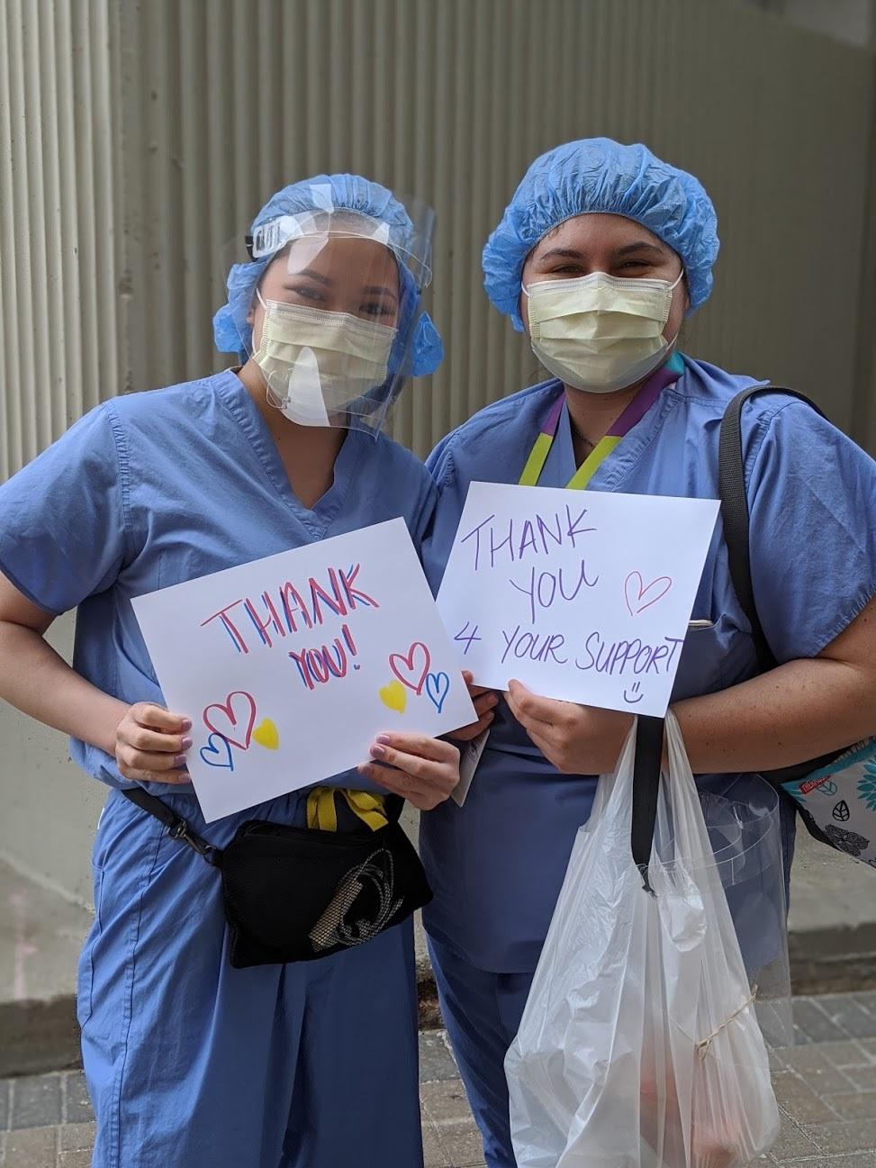 Two staff with thank you signs Two staff with thank you signs