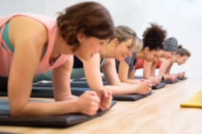 several women in fitness class lying down on forearms 