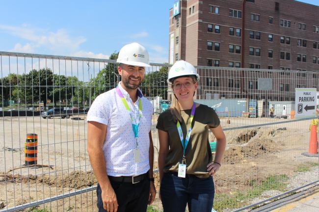 man and woman standing in front of construction site wearing hardhats