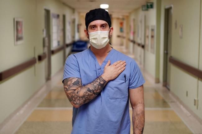 man standing in hospital corridor with hand over heart