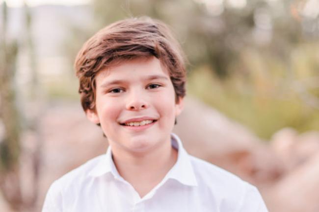 Karsten, a young boy wearing a white shirt, standing facing the camera 