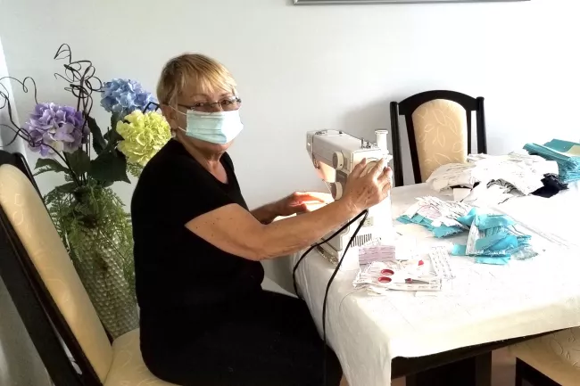 woman sitting at table behind sewing machine