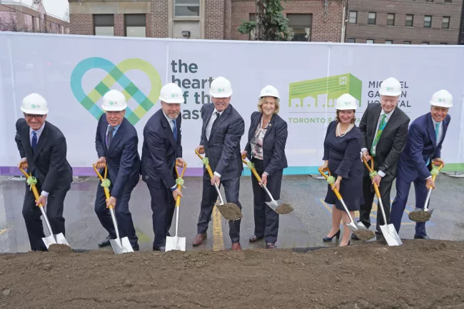 executives pose with shovels in front of HOTE banner
