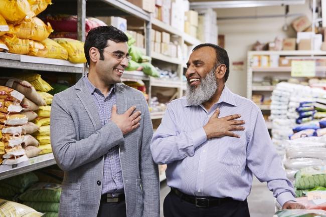 two men standing side by side slightly turned to face each other each with right hand over heart