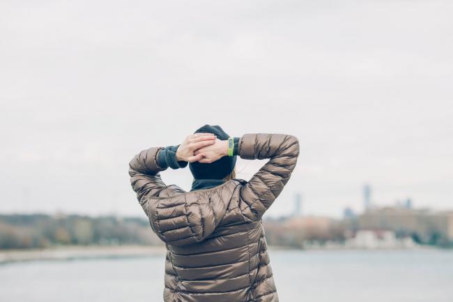 man holding behind head looking at water