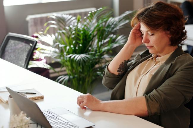 Woman at work desk holding her head