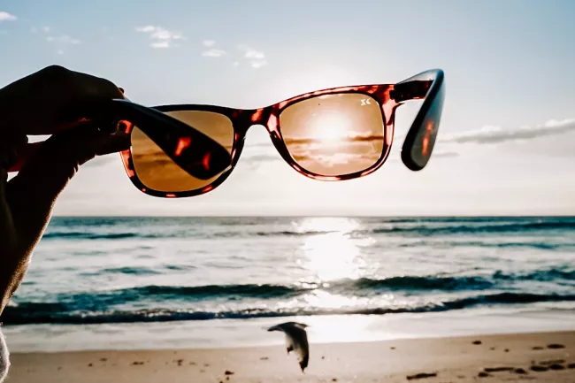 hand holding sunglasses against sun  hand holding sunglasses against sun