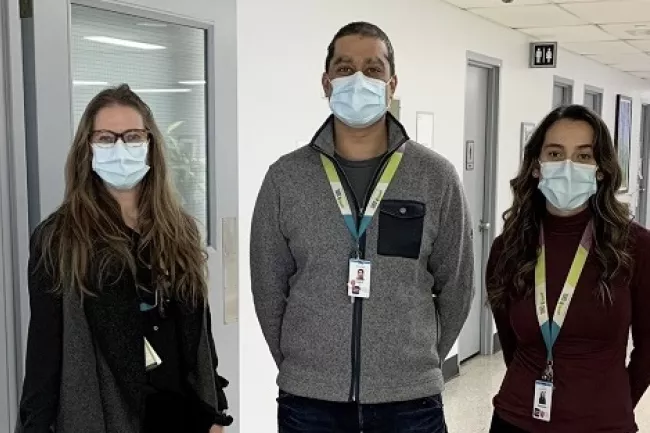 three people standing in corridor facing the camera 