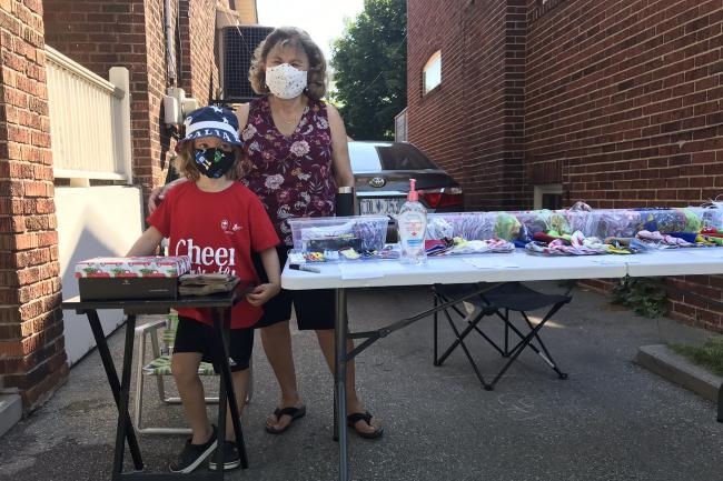 woman and boy standing next to table of masks 