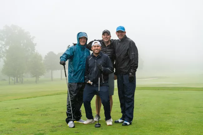 Golfers posing in the rain at the Golf Classic 2023