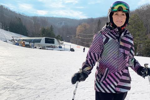 Margrie, an older white woman, on a ski hill with poles and googles.